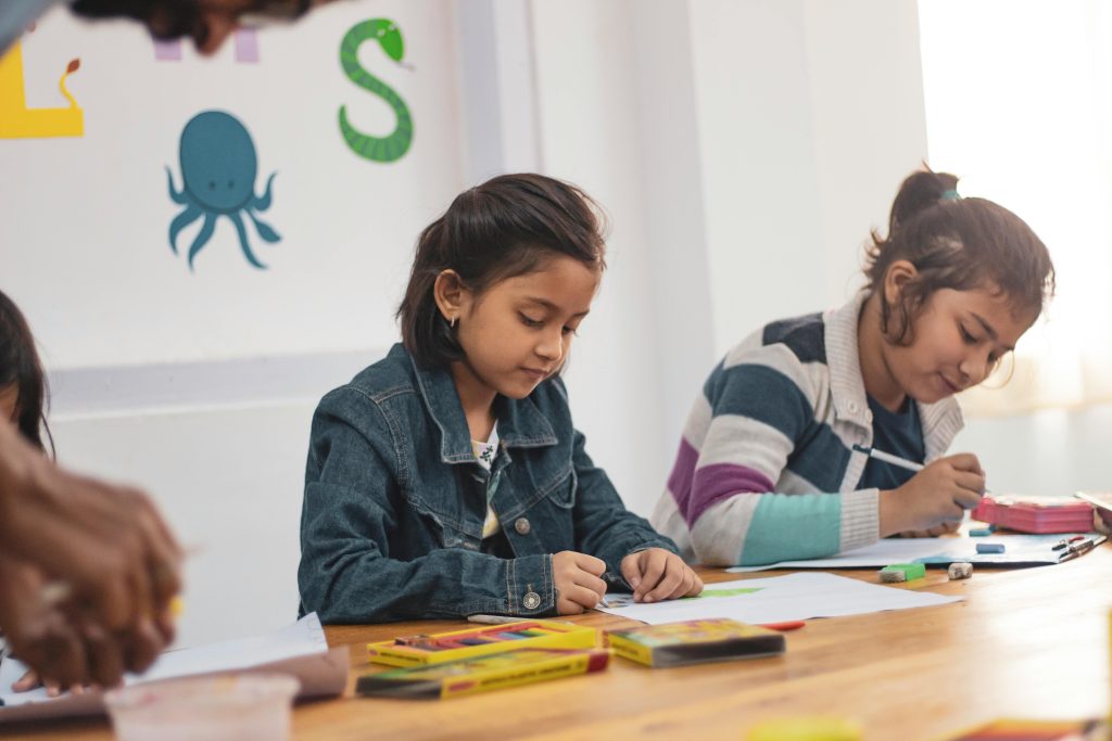 Young girls engaging in creative drawing activities in an Indian classroom setting.
